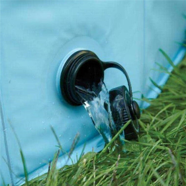 Drain valve of a foldable dog swimming pool with water flowing out onto the grass.