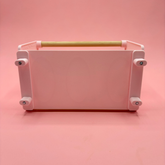 cage mounted hay rack in pastel pink color on a pink background, ideal for keeping hay organized and tidy.