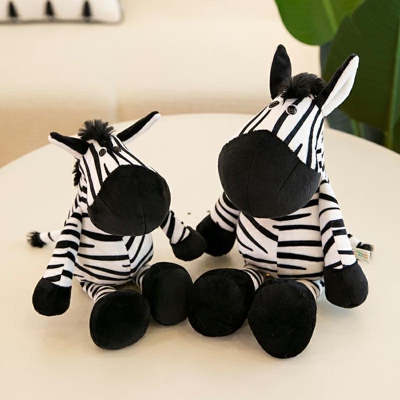 Safari adventure plush toys featuring two adorable zebra plushies with black and white stripes on a table.