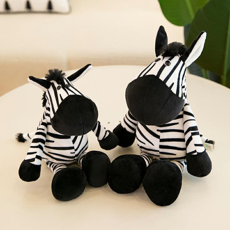 Safari adventure plush toys featuring two adorable zebra plushies with black and white stripes on a table.