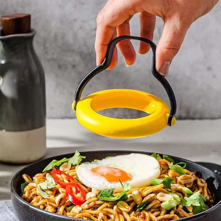 Hand holding an anti-leakage fried egg mold over a bowl of noodles topped with a fried egg and herbs.